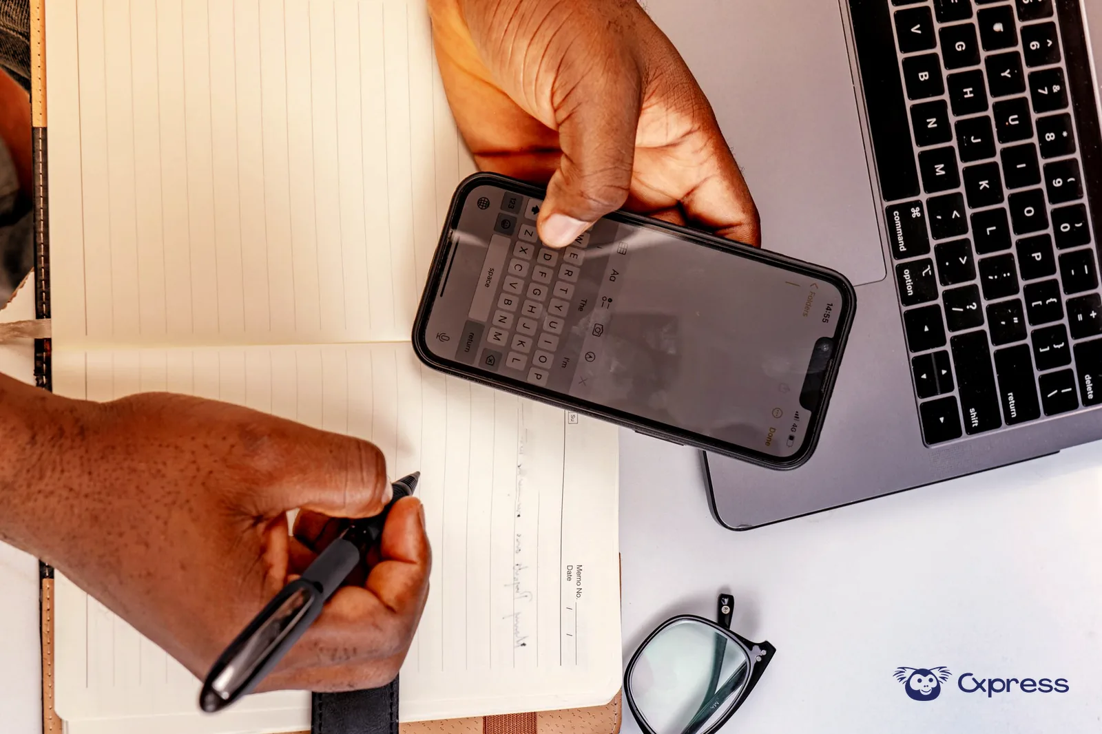 Mãos a comparar um número de telefone no telemóvel com informação aberta num computador